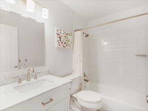 Full bath featuring vanity, toilet, and shower / bath combination with curtain