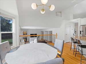 Dining space with high vaulted ceiling, light wood-type flooring, and a tiled fireplace