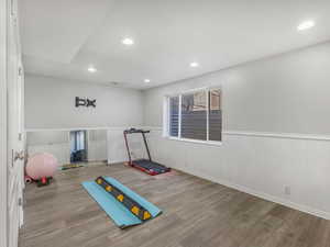 Workout room with a wainscoted wall, wood finished floors, and recessed lighting