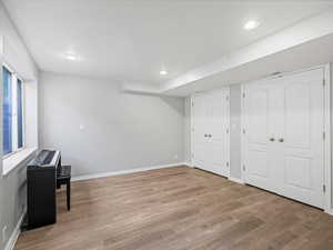 Basement with light wood-style flooring, baseboards, and recessed lighting
