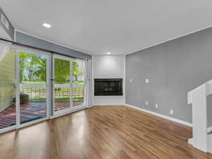 Unfurnished living room with baseboards, wood finished floors, a multi sided fireplace, and recessed lighting
