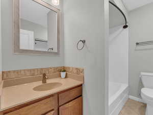 Bathroom with toilet, tile patterned floors, and vanity