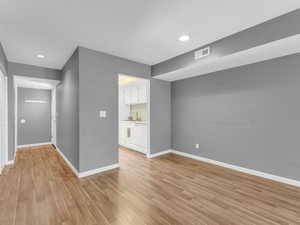 Spare room with light wood-style floors, baseboards, a sink, and recessed lighting
