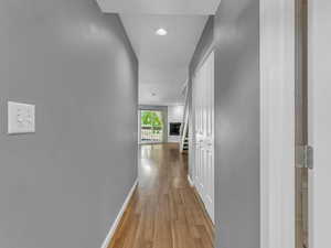Hallway with baseboards, wood finished floors, a textured wall, and recessed lighting