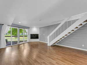 Unfurnished living room featuring baseboards, stairway, wood finished floors, recessed lighting, and a fireplace