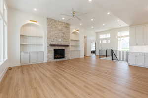 Unfurnished living room with a ceiling fan, built in features, light wood-style floors, recessed lighting, and baseboards
