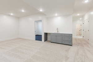 Basement featuring light colored carpet, wet bar, baseboards, and recessed lighting