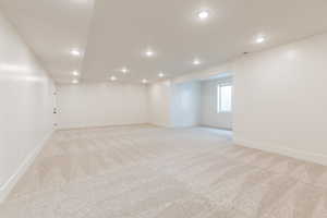 Empty room featuring light colored carpet, baseboards, and recessed lighting