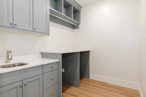 Laundry area featuring a sink, light wood-style floors, and baseboards