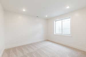 Spare room featuring light carpet, baseboards, and recessed lighting