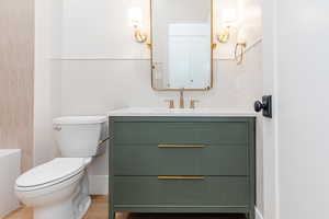 Bathroom with vanity, toilet, a wainscoted wall, and a shower