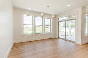 Spare room with baseboards, a chandelier, light wood-style floors, and recessed lighting
