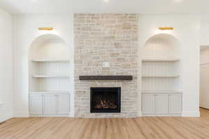 Unfurnished living room with wood finished floors, a fireplace, built in features, and baseboards