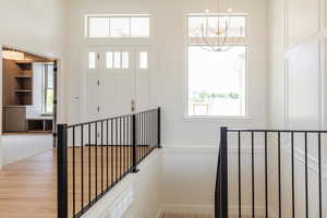 Entrance foyer with a chandelier, a towering ceiling, baseboards, and light wood finished floors