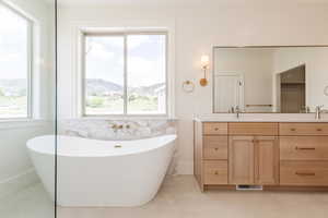 Bathroom with double vanity, a freestanding tub, tile patterned flooring, and a mountain view