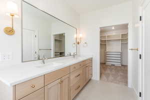 Full bathroom with double vanity, a walk in closet, tile patterned flooring, and baseboards