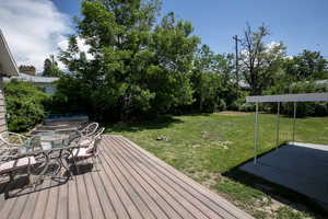 Wooden deck featuring outdoor dining area and a lawn