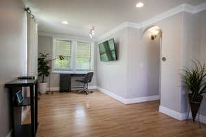 Office space with wood finished floors, baseboards, arched walkways, crown molding, and recessed lighting