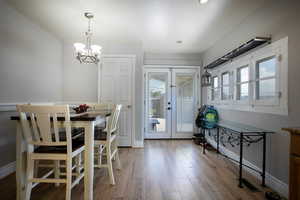 Dining space with a chandelier, french doors, light wood finished floors, and baseboards