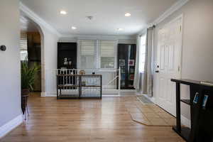 Entrance foyer with wood finished floors, crown molding, arched walkways, recessed lighting, and baseboards