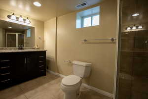 Full bath featuring vanity, toilet, a shower stall, tile patterned flooring, and baseboards