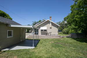 Back of property with a chimney, a lawn, and a patio