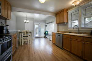 Kitchen featuring stainless steel appliances, a sink, arched walkways, and brown cabinetry
