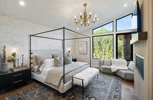 Bedroom with a chandelier, wood finished floors, lofted ceiling, a fireplace, and recessed lighting