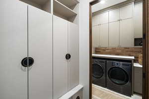 Laundry area featuring washing machine and clothes dryer and cabinet space