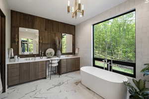 Bathroom with two vanities, a freestanding tub, marble finish flooring, tile walls, and a chandelier