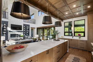 Kitchen featuring wood ceiling with exposed beams, brown cabinetry, open floor plan, dark wood-style flooring, and light stone counters
