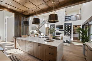 Kitchen featuring wood ceiling with exposed beams, wood finished floors, modern cabinets, baseboards, and light stone countertops