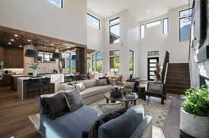 Living area with hardwood / wood-style flooring, plenty of natural light, a high ceiling, stairway, and recessed lighting