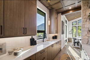 Kitchen with wooden ceiling with exposed beams, a sink, light wood-style floors, plenty of natural light, and tasteful backsplash