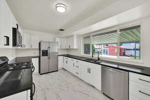 Upstairs Kitchen with new; Flooring, cabinets, appliances, light fixture, quartz counters, large window for natural light and view of the backyard