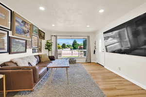 Big picture window with natural light, can lighting and hardwood floors in the front living room