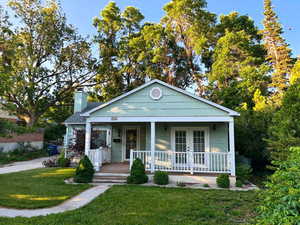 Bungalow-style home featuring covered porch, a front lawn, and a chimney