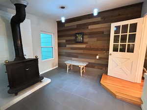 Mudroom with a wood stove, dark tile patterned floors, and wooden walls
