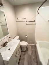 Bathroom featuring vanity, toilet, baseboards, and shower / tub combination