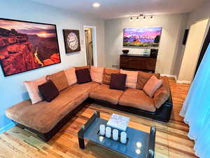Living area with wood finished floors, baseboards, and recessed lighting