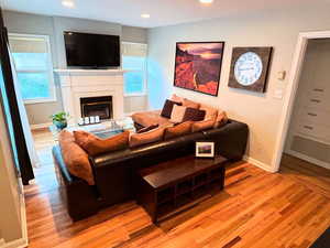 Living room featuring light wood finished floors, baseboards, recessed lighting, and a glass covered fireplace
