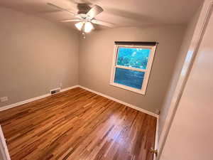 Unfurnished room with wood finished floors, ceiling fan, and baseboards