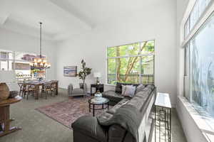 Carpeted living room featuring healthy amount of natural light, a chandelier, and a towering ceiling