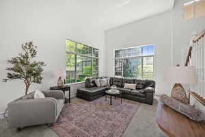 Carpeted living area featuring vaulted ceilings, with a healthy amount of natural light