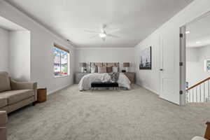 Carpeted primary bedroom featuring ceiling fan, and ornamental molding.