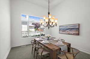 Carpeted formal dining space with a large chandelier