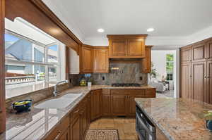 Kitchen with a sink, ornamental molding, gas stovetop, backsplash, and light granite counters.
