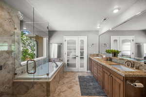 Bathroom with double vanity, a bath, a stall shower, and french doors.