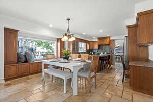 Dining room featuring stone tile flooring, recessed lighting, and chandelier.
