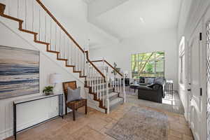 Foyer entrance featuring stone floors, stairway, and a high ceiling